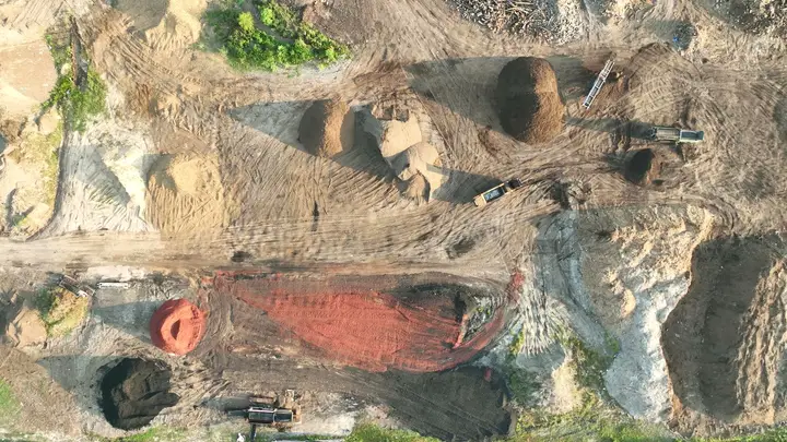 Aerial looking straight down on the Casco Organics production yard: compost windrows, red mulch, sand and wood piles, and equipment on the haul roads